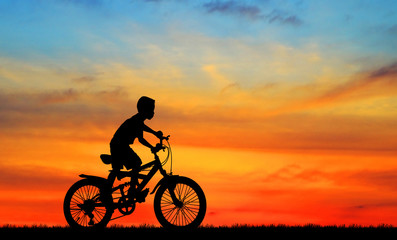 Fototapeta na wymiar Silhouette boy and bike relaxing on sunrise