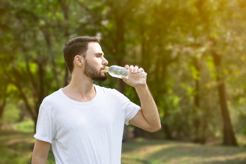 portrait of a young man drinking water in park