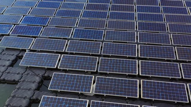 Solar panels in aerial view, rows array of polycrystalline silicon solar cells or photovoltaics in solar power plant floating on the water in lake.