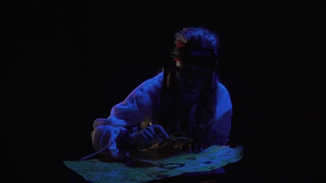 Female pirate is sitting in front of the map with a magnifier at night, 4k