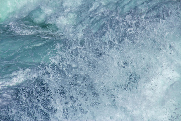Aquatic background of sea surf waves splashing close up with clear blue green water and white foam