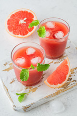 Ripe cut grapefruits and glass of freshly squeezed grapefruit juice