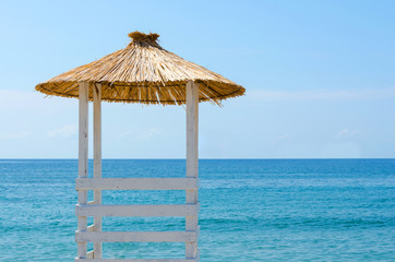 Ligeguard place with reed umbrela. Travel to a tropical country concept.