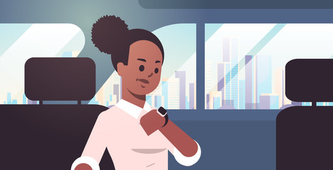 young businesswoman checking time african american woman car passenger sitting on back seat in taxi cab city transportation service concept flat portrait horizontal © mast3r