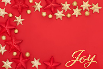 Christmas background with gold joy sign, star and bauble decorations on red forming an abstract border with copy space. Traditional greetings card for the festive season.