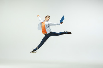 Fototapeta na wymiar Happy young man working at office, jumping and dancing in casual clothes or suit isolated on white studio background. Business, start-up, working open-space, ballet or professional occupation concept.