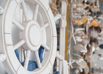 A white rudder on a wall with decoration stuff at the background.