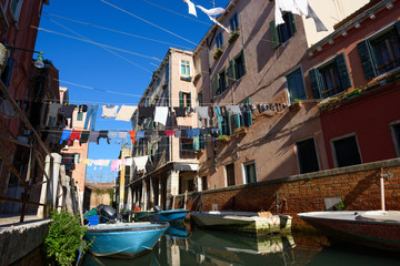 Fototapeta na wymiar Venice Italy street with laundry washed clothes hanging out to dry on ropes between houses over the canal