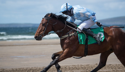 Galloping race horse and jockey on the beach