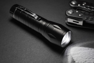 black flashlight on the stone surface. Tools for work, search and tourism ..