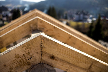 Close-up detail of roof frame of rough wooden lumber beams on background of misty mountain landscape in ecological area. Building, roofing, construction and renovation concept.