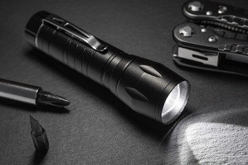 black flashlight on the stone surface. Tools for work, search and tourism ..