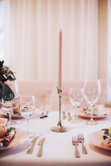 Romantic table setting in pink tones with pink candle.