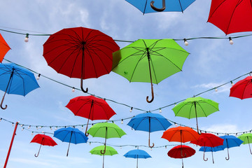 Colorful umbrellas and lightbulbs, sky in the background. Selective focus.