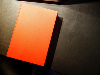 Red hardback book on black table, Office dark table. 