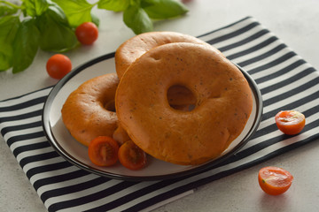 Bagels isolated on bright board with basil and cherry tomatoes for breakfast. Pastry.