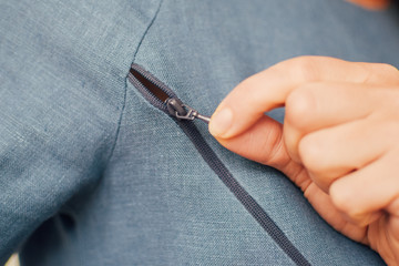 Young woman unzip natural linen blue nursing cloth pulling pawl at the pocket by hand, handmade...