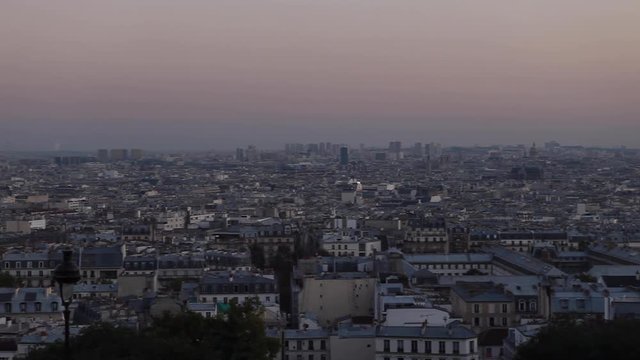 Beautiful aerial view of a huge Parisian landscape from the heights of Montmartre at the end of the day with a blue orange sky in Paris. Pan to left on old buildings, lamp posts, skyscrapers.