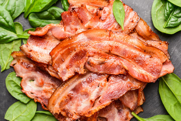 Fried bacon with herbs on dark background, closeup