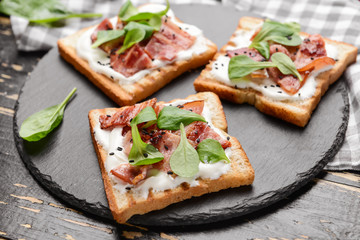 Slate plate with tasty toasts on dark table