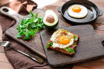 Tasty toast with bacon and fried egg on wooden table
