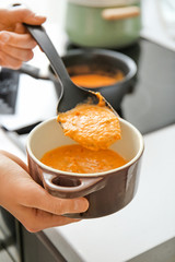 Woman pouring delicious cream soup into pot, closeup