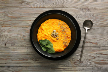 Bowl with delicious pumpkin cream soup on wooden table