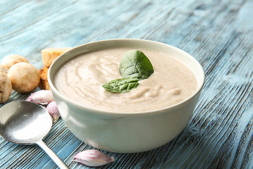 Bowl with delicious mushroom cream soup on wooden table