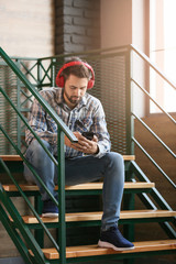 Fototapeta premium Young man listening to audiobook indoors