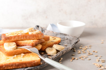 Plate with tasty French toasts and banana on grey table