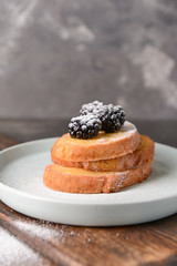 Plate with tasty French toasts and blackberry on table