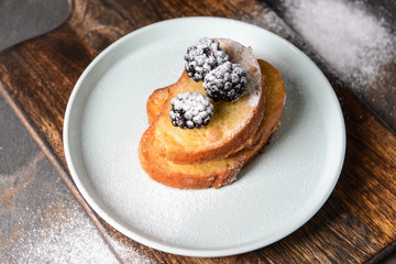 Plate with tasty French toasts and blackberry on table