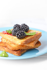 Plate with tasty French toasts and blackberry on white table