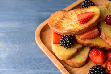 Plate with tasty French toasts and berries on wooden table