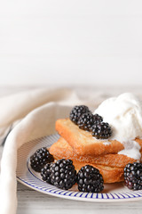 Plate with tasty French toasts, ice cream and blackberry on table
