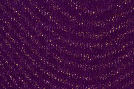 Dark violet textile background with a metallic Lurex gold thread. Plum matte fabric interspersed with shiny sequins.