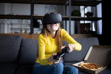 Cute girl plays the game on the console and eats pizza. VR experience