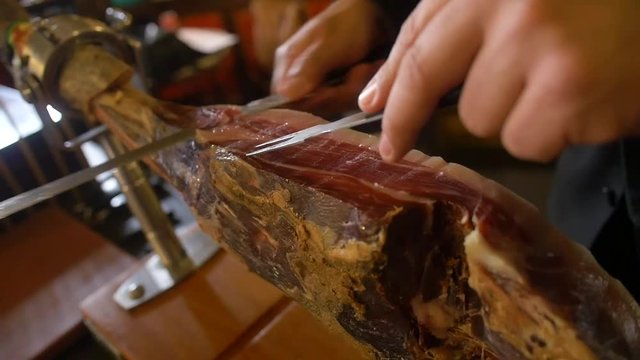 Traditional serrano ham being sliced and served in Spain.