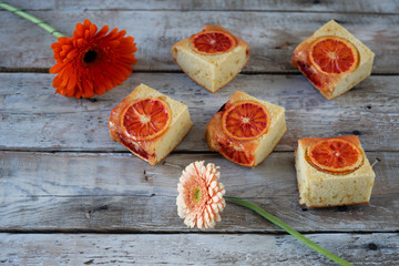 Pieces of Homemade cake with blood oranges on light wooden background. Top view of layout, copy...