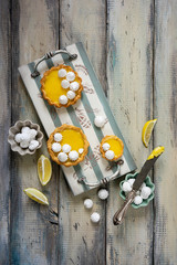Lemon tarts with lemon curd and white meringues on vintage wooden table. Top view. Copy space