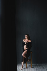 Fototapeta na wymiar Pregnant caucasian long-haired woman in a beautiful dress holding her hands on her belly. Pregnancy, happiness, expectation concept.