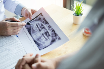 Medical team discussing, health care talking to female patient, Medical conferrence concept, doctor holding and looking at dental x-ray attending a client.