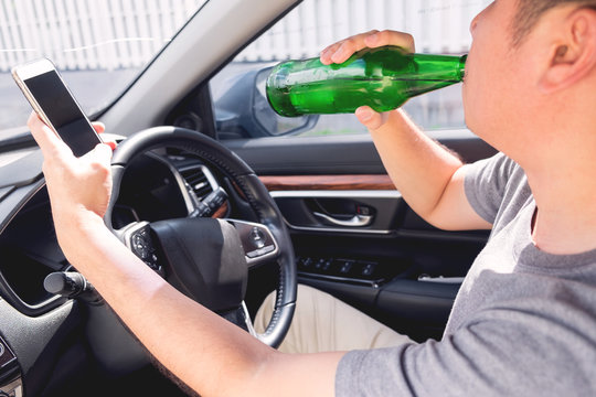 Don't Drink for Drive concept, Young Drunk man drinking bottle of beer or alcohol during driving the car dangerously