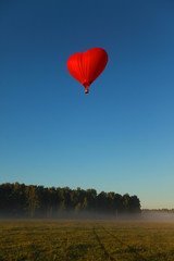 Obraz premium beautiful summer sunny nature landscape with a flying heart-shaped balloon in the blue sky