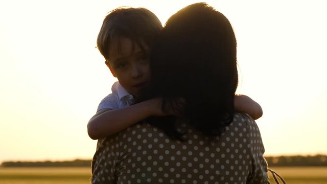 Portrait of a little boy. The sun's rays touch the child's face, embracing his mother and son experiencing emotions of happiness and pleasure.