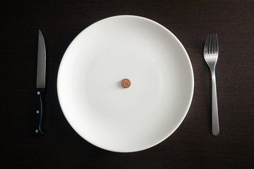 Healthy food, poverty, saving money: coins on a white plate at d