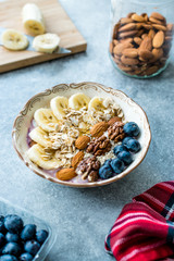 Acai Bowl with Yogurt, Blackberry, Banana Slices, Walnut, Honey, Jam, Oat, Almond, Sesame Seeds and Granola in Porcelain Bowl.