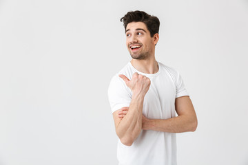 Happy young excited emotional man posing isolated over white wall background. Looking aside.