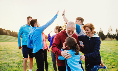 Large group of fit and active people resting after doing exercise in nature.