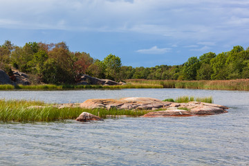 Unusual red stony coast of Baltic sea surrounded with forest on the Aland islands, Finland